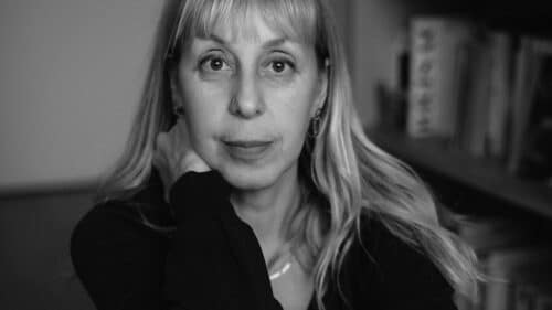 Portrait de Lola Lafon, assise devant une bibliothèque