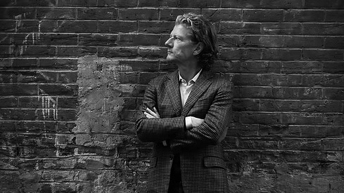 Portrait de Andreas Wimmer croisant les bras devant un mur de briques